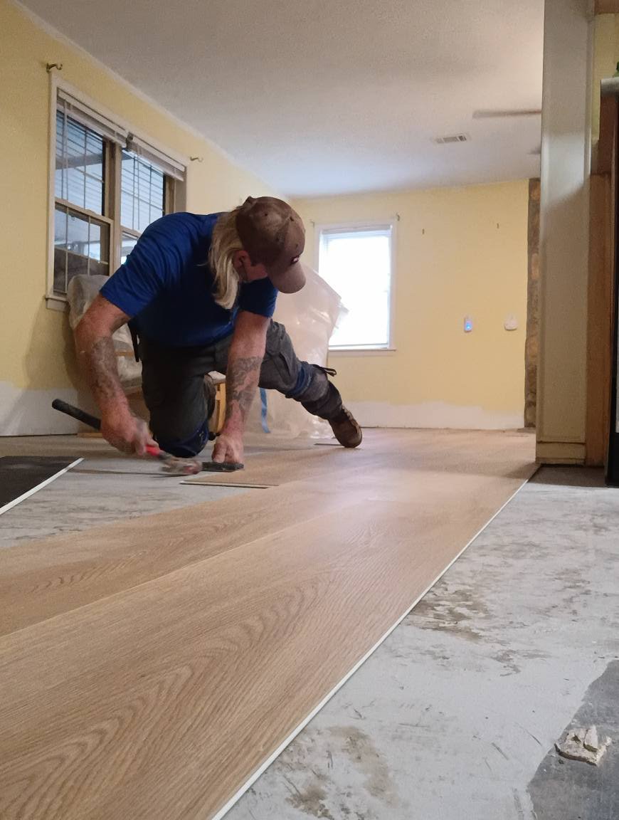 Installer placing wide plank LVP flooring
